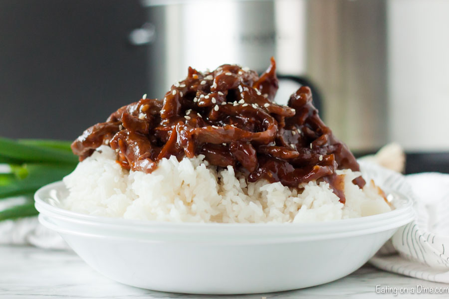 Close up image of Mongolian Beef on white rice in a white bowl.