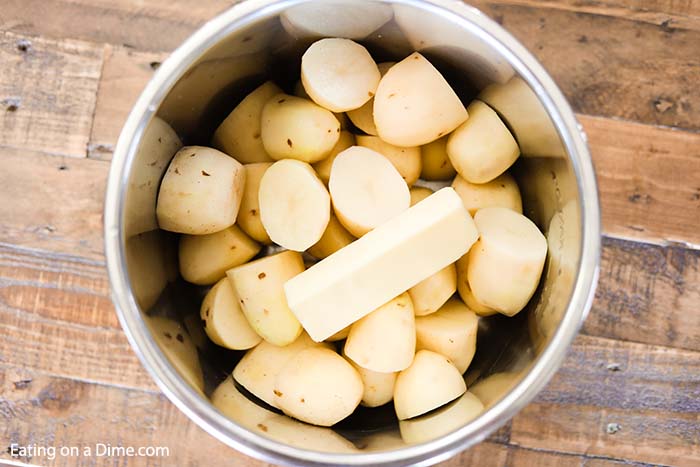 Close up image of potatoes in the instant pot with a stick of butter. 