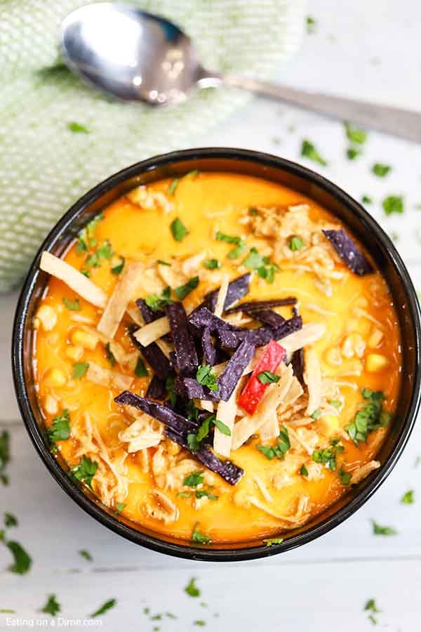 Bowl of creamy chicken tortilla soup topped with tortilla strips and cilantro. 