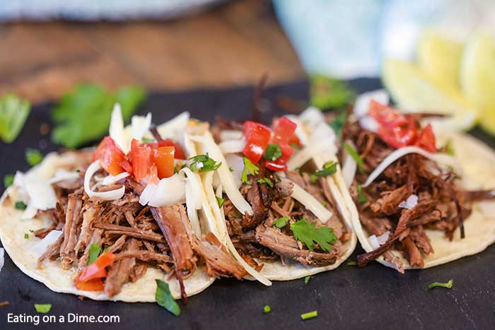 Beef Carnitas Tacos on a platter with a side of fresh limes