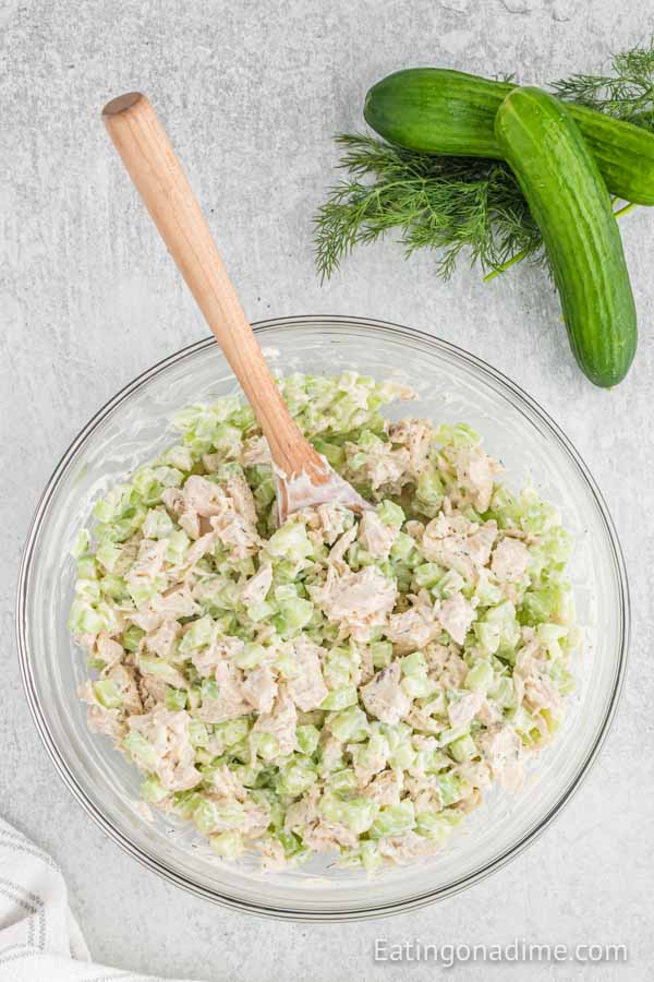 Close up image of cucumber chicken salad in a bowl with a wooden spoon