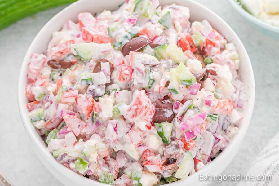 A close up image of creamy greek salad in a bowl