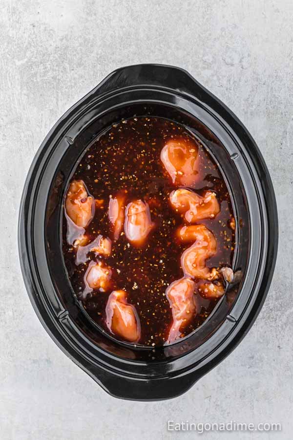 Uncooked chicken thighs in the crock pot with honey garlic sauce