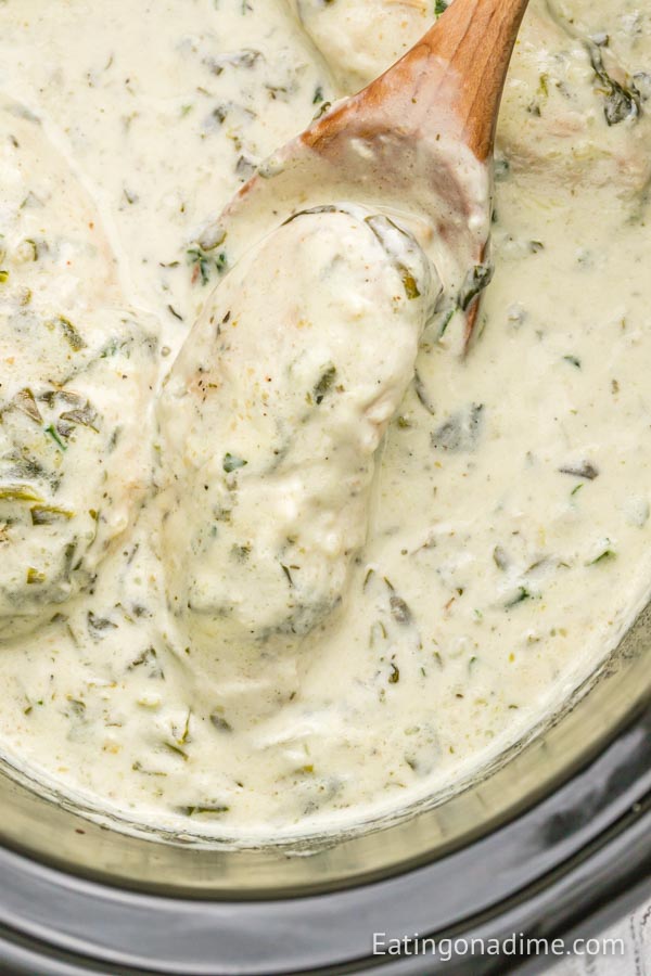 Chicken Florentine in the crock pot with a wooden spoon