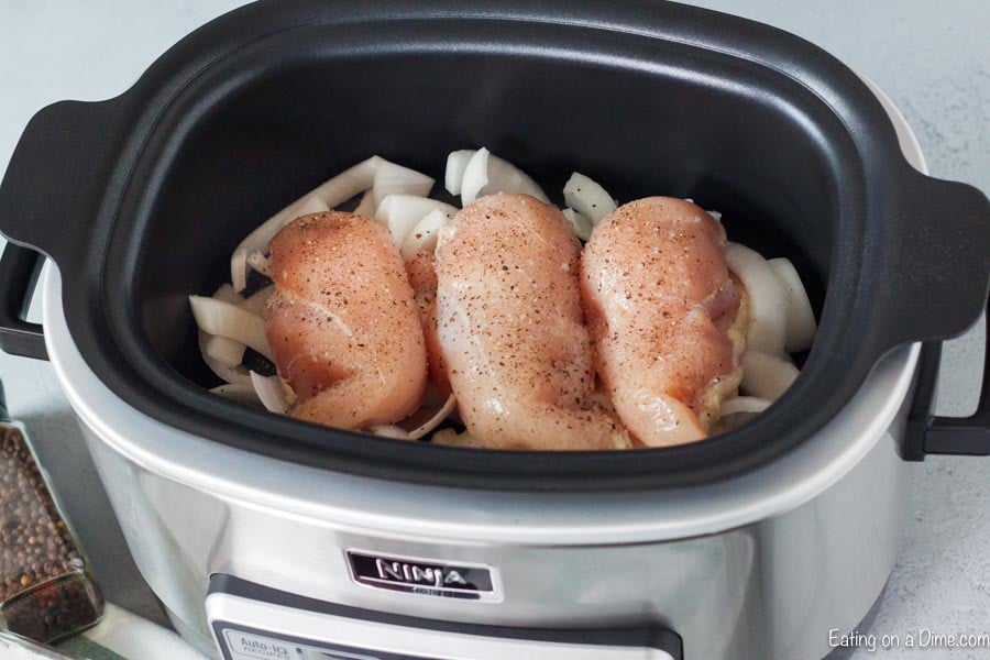 raw chicken on onion in crock pot