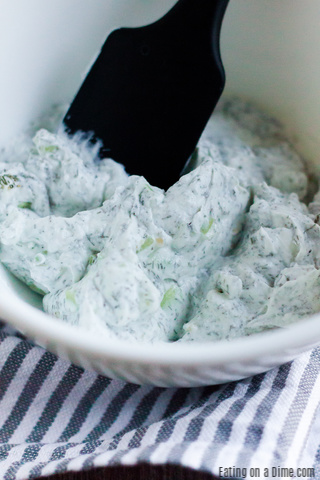 Combining the ingredients for Tzatziki Sauce in a bowl with a spatula