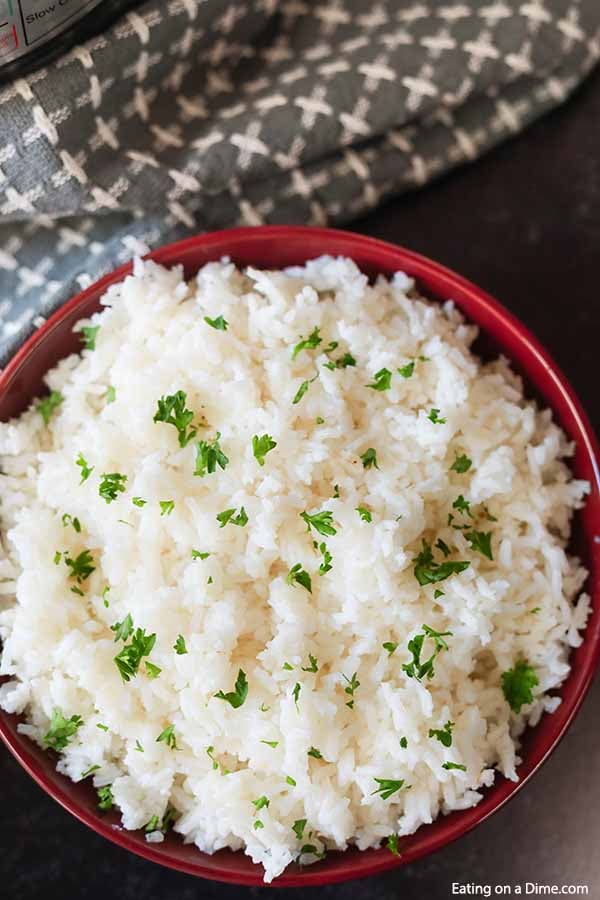 closeup photo of white rice in red bowl with parsley on top