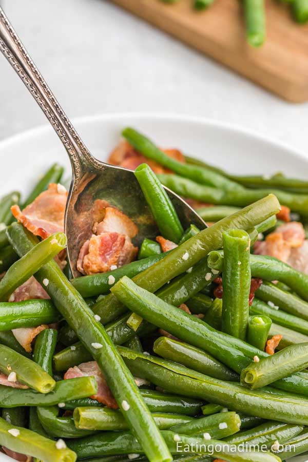 Green beans with bacon in a bowl with a spoon 