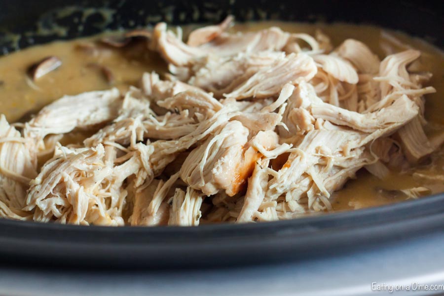 Shredded chicken on top of the creamy mixture in the slow cooker