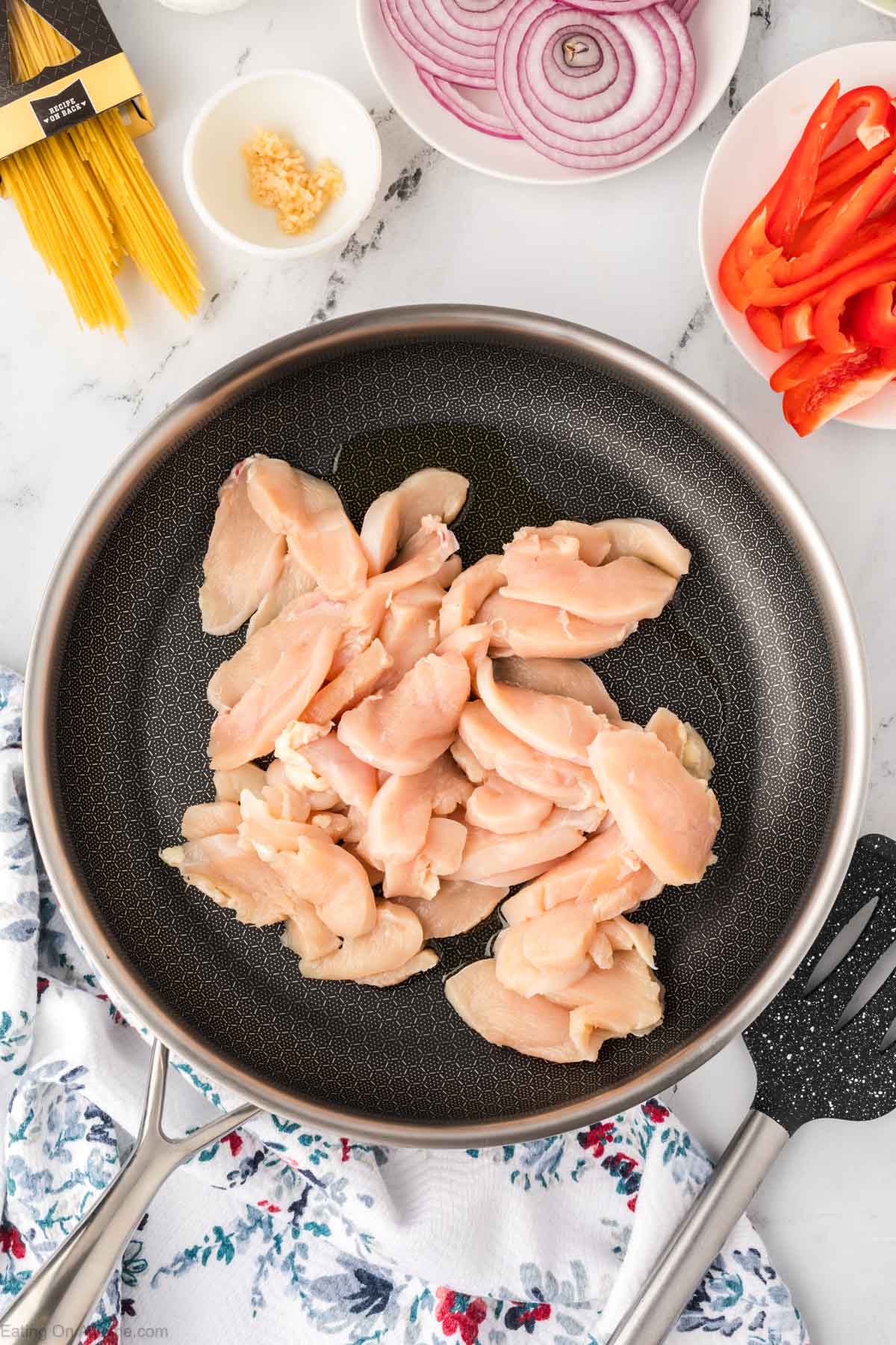 Placing chicken in a skillet to cook