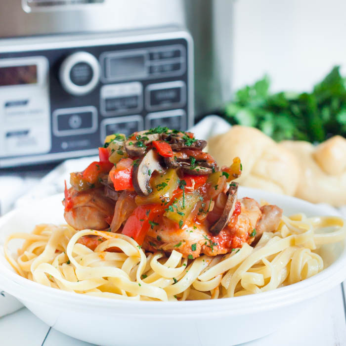 Chicken Cacciatore served over fettuccini noodles in a bowl 