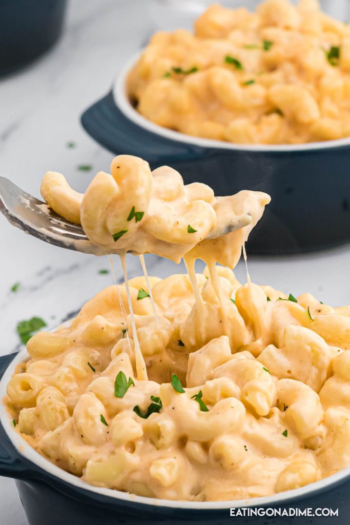 Close up image of blue bowls of macaroni and cheese with a serving on a fork. 