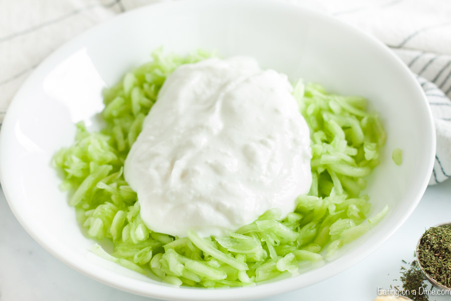 Close up image of shredded cucumber with a serving of greek yogurt on top. 