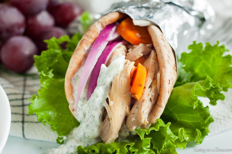 Chicken Gyro with Tzatziki Sauce in a pita bread wrapped in foil topped with onion and tomato