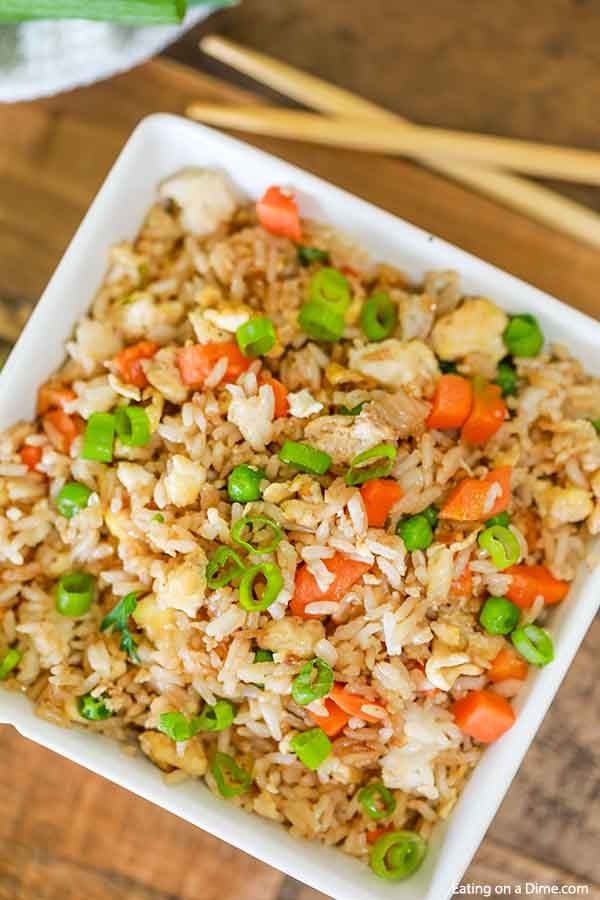 Large bowl of fried rice with chop sticks laying next to the bowl of fried rice.  