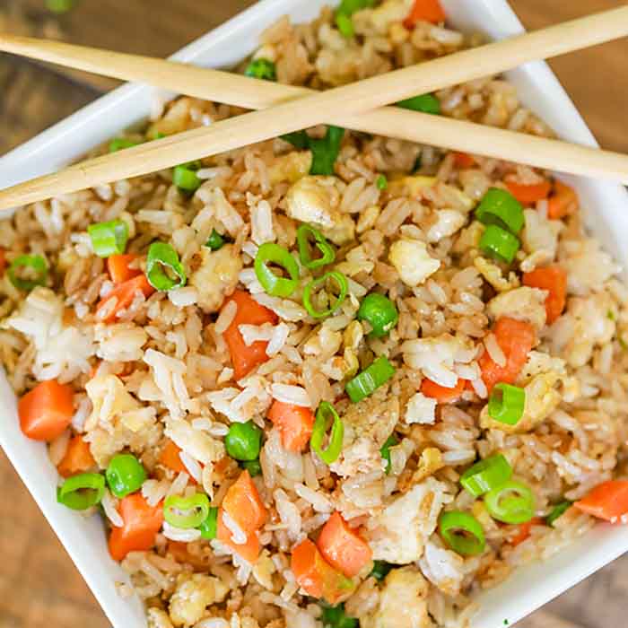 Large bowl of fried rice with chop sticks on top.  