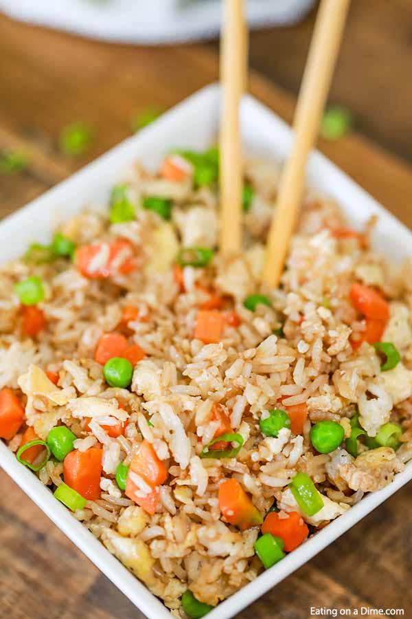 Close up of a large bowl of fried rice with chop sticks in the bowl of fried rice  