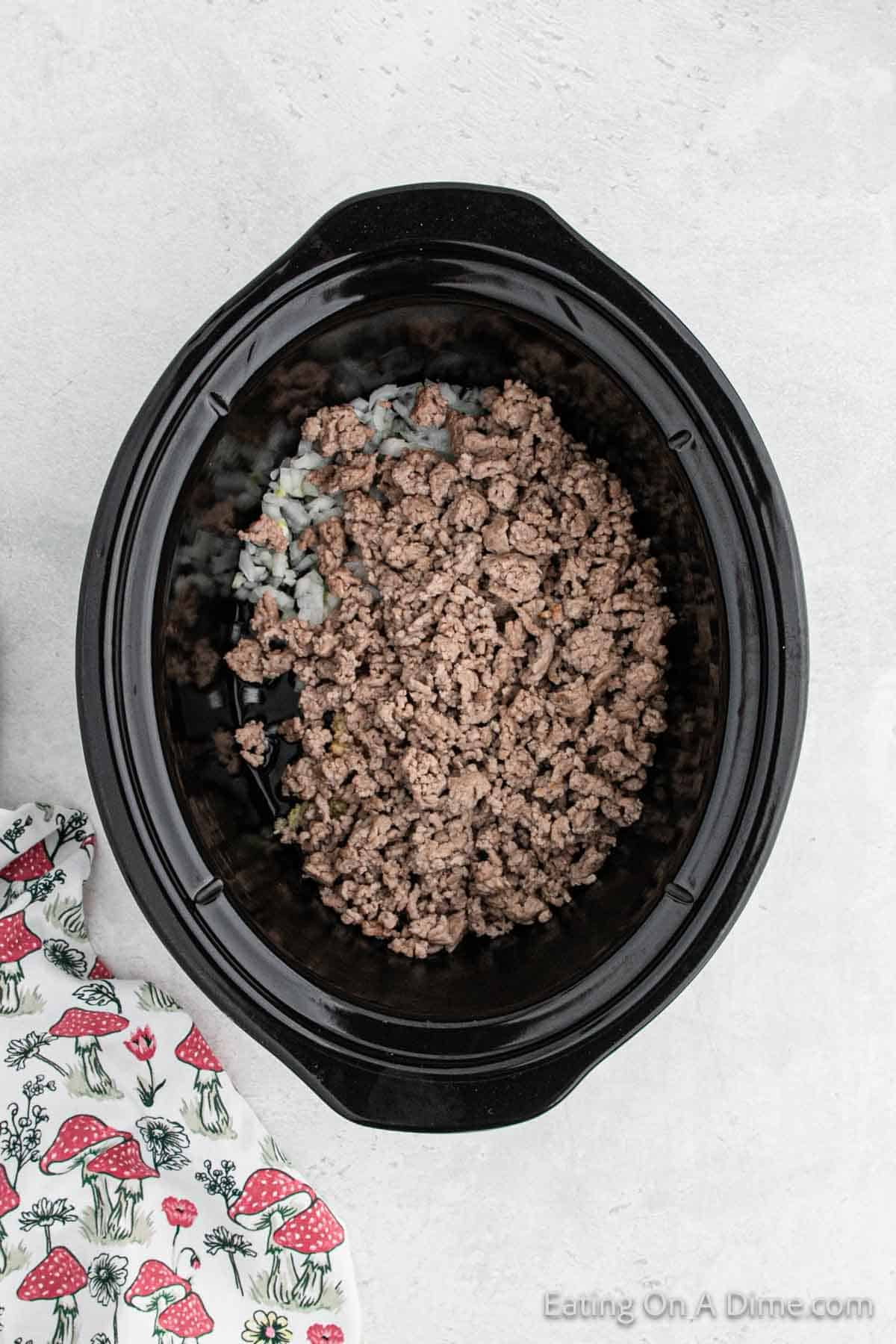 Placing the onions, garlic and ground beef in the slow cooker