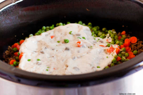 Frozen peas and carrots in a slow cooker topped with cream of mushroom soup