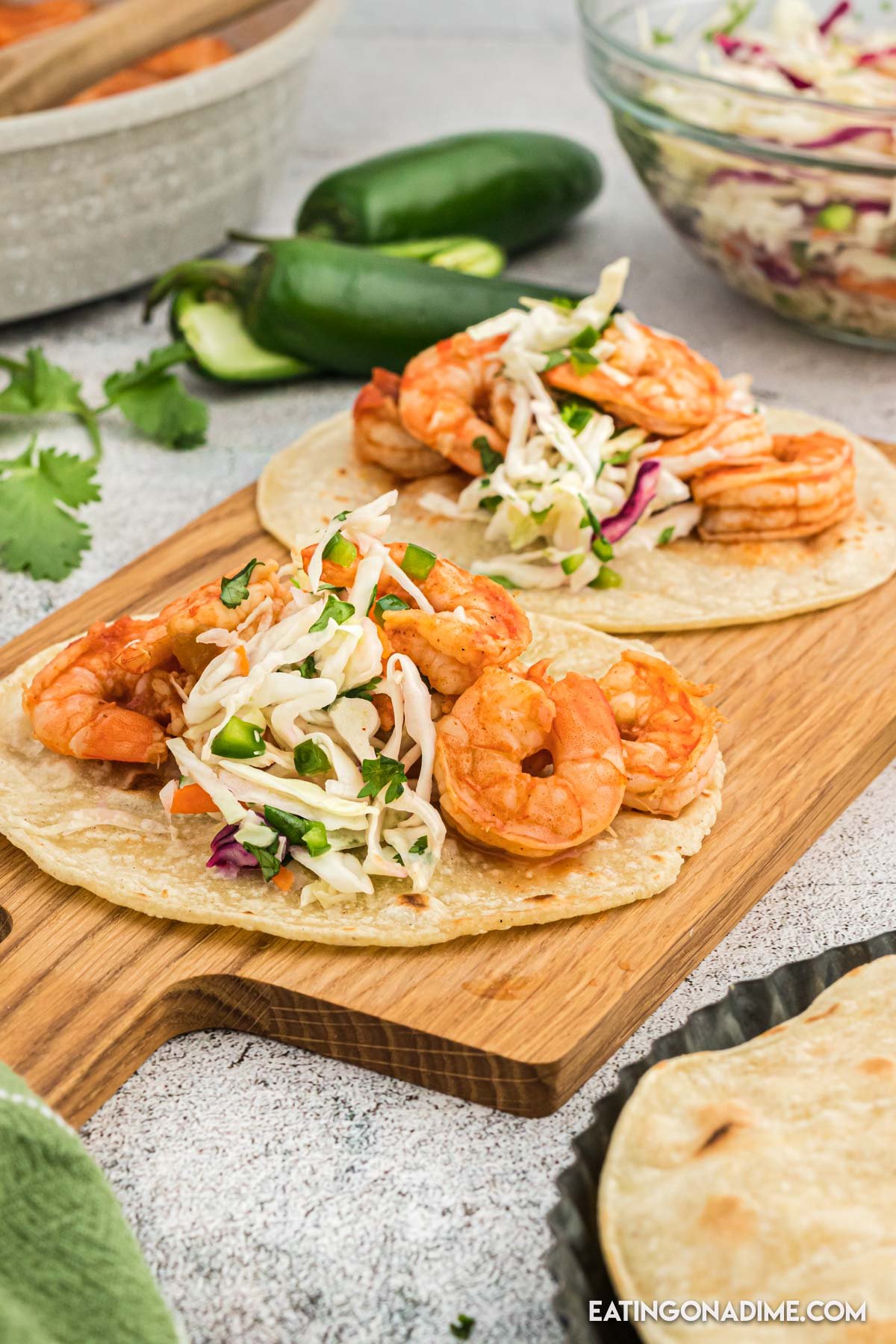 Close up image of shrimp tacos on a platter with a jalapenos on the side