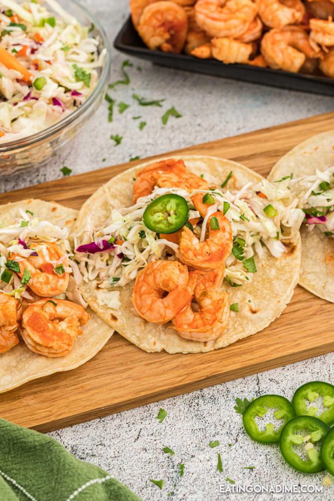 Close up image of shrimp tacos on a platter with a jalapenos on the side