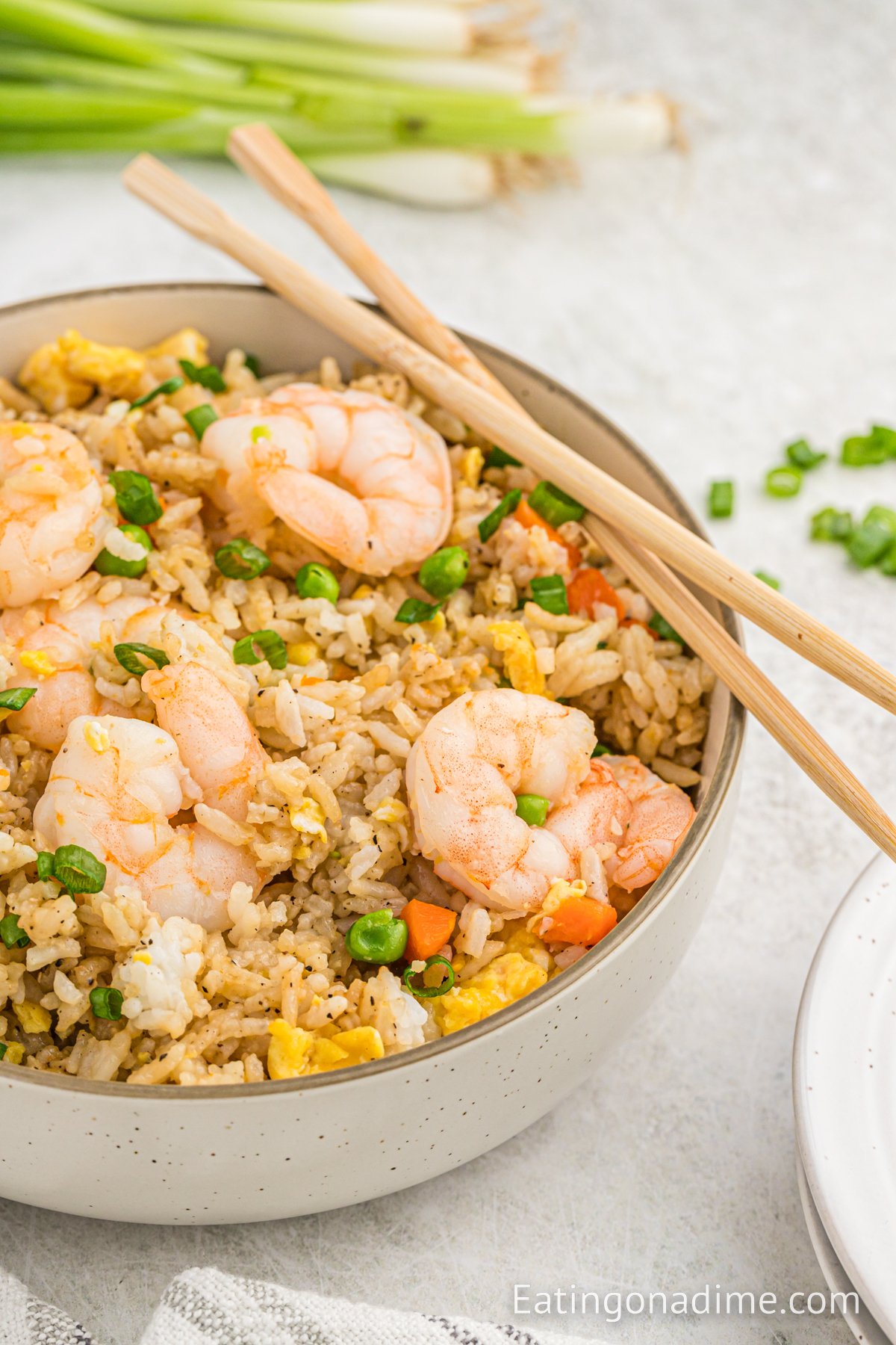 Close up image of shrimp fried rice in a dish with chopsticks