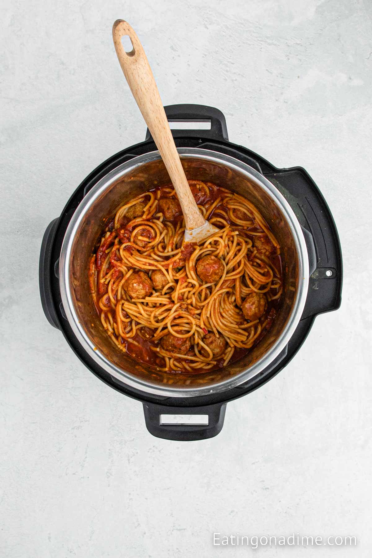 Spaghetti and Meatballs in a pressure cooker with a wooden spoon