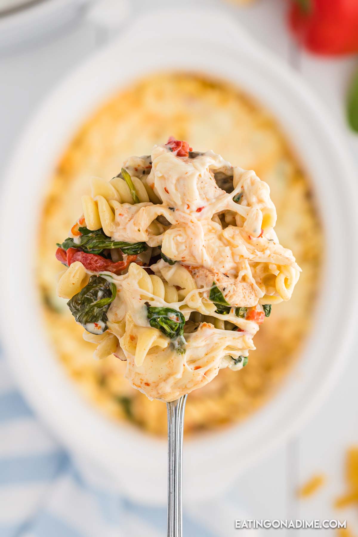 Close up image of a serving of red roasted chicken pasta on a spoon