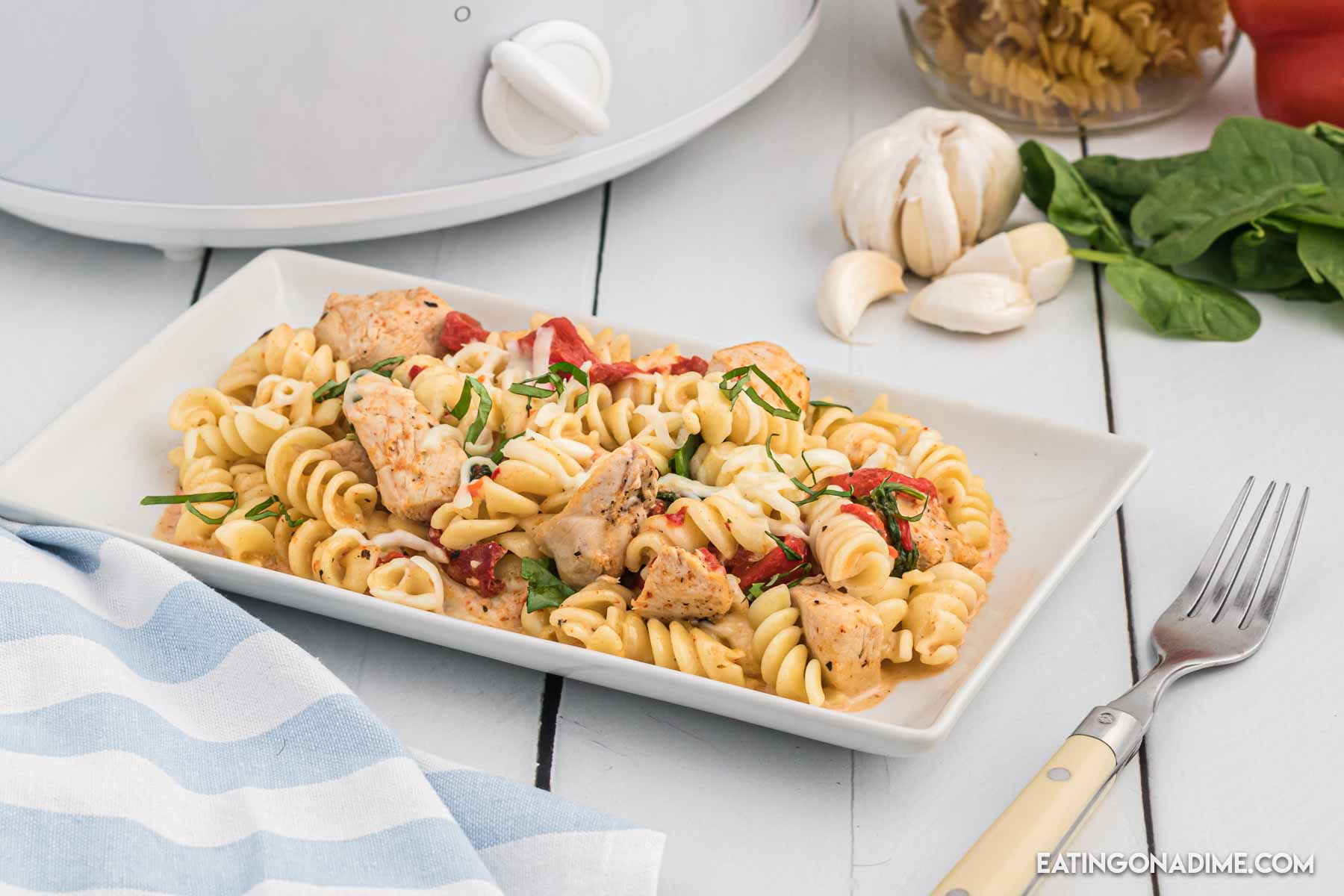Close up image of red roasted chicken pasta on a white plate