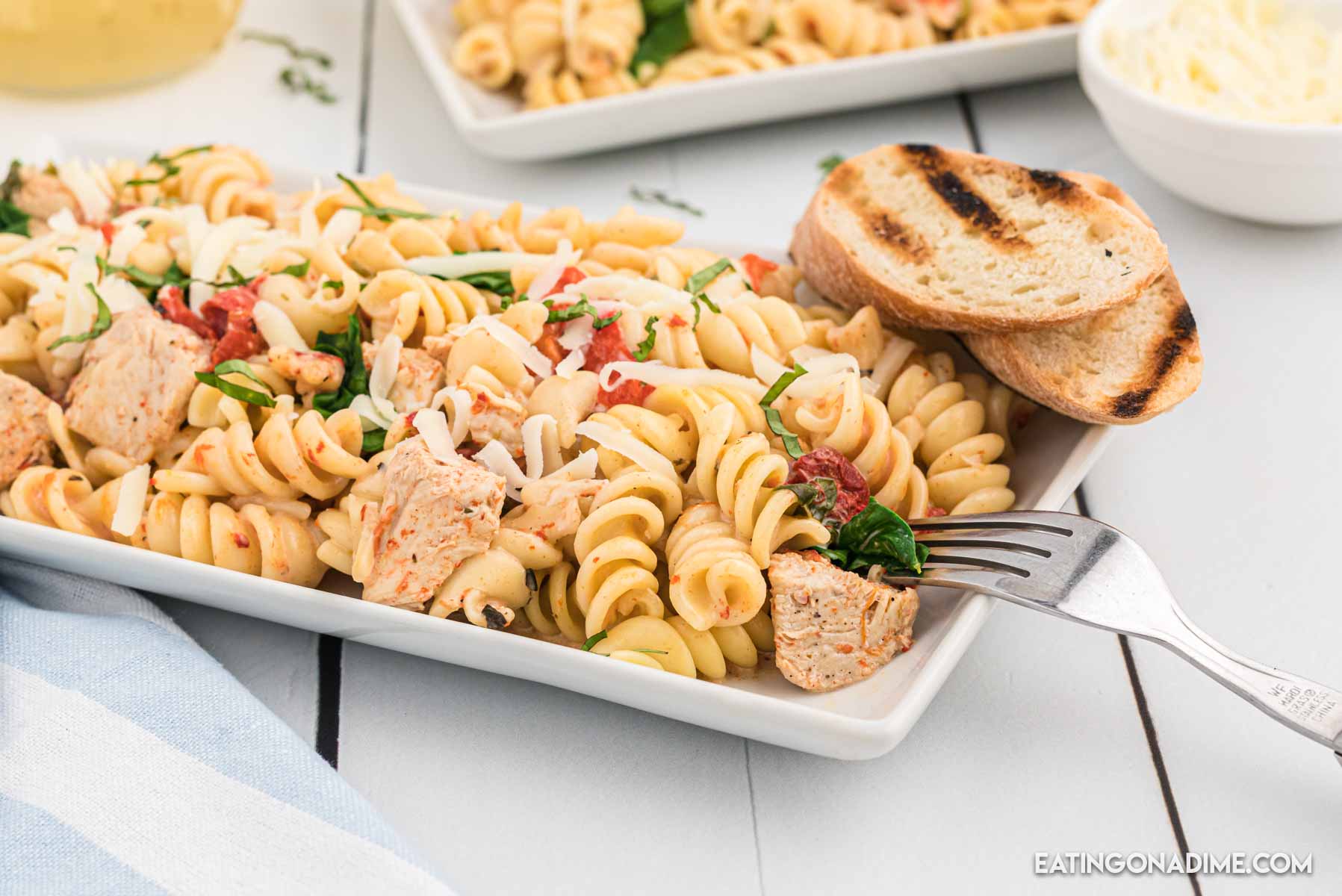 Close up image of red roasted chicken pasta on a white plate