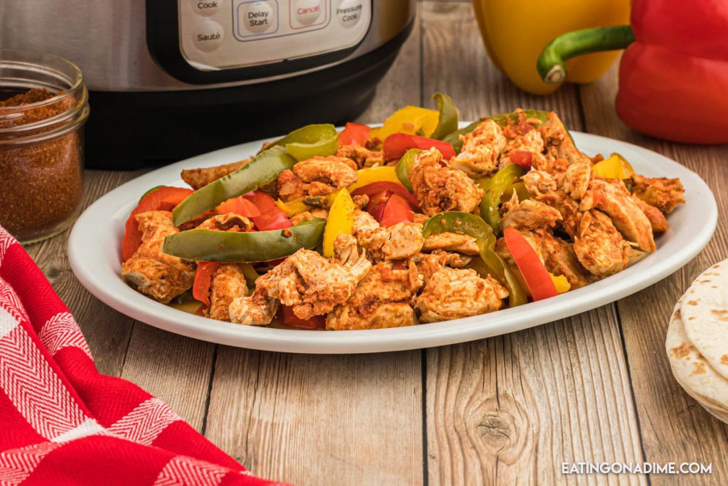Close up image of chicken fajita with peppers on a white plate