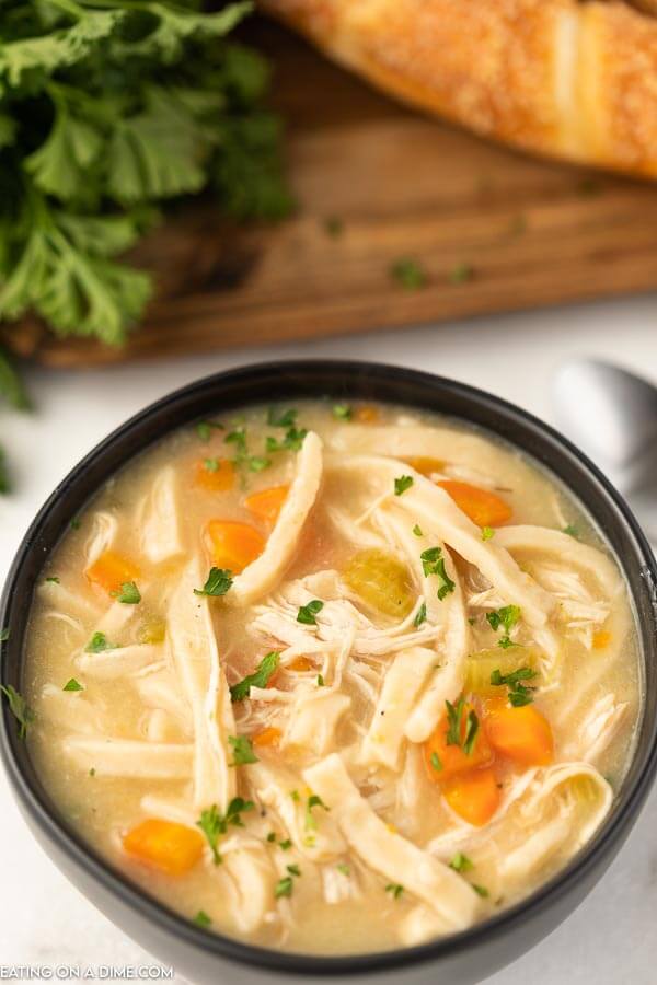 Close up image of a black bowl of chicken noodle soup. 