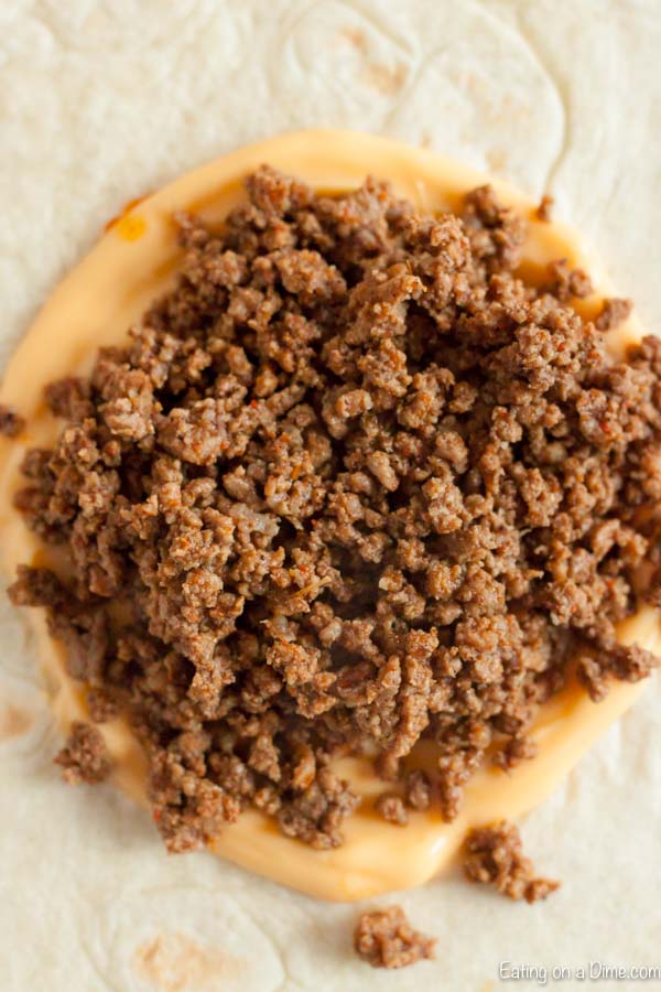 Topping the tortilla with cheese and ground beef
