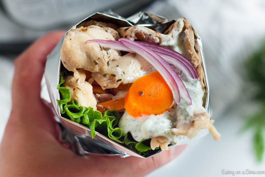 Close up image of chicken gyro with carrots and lettuce and some tzatziki sauce. 