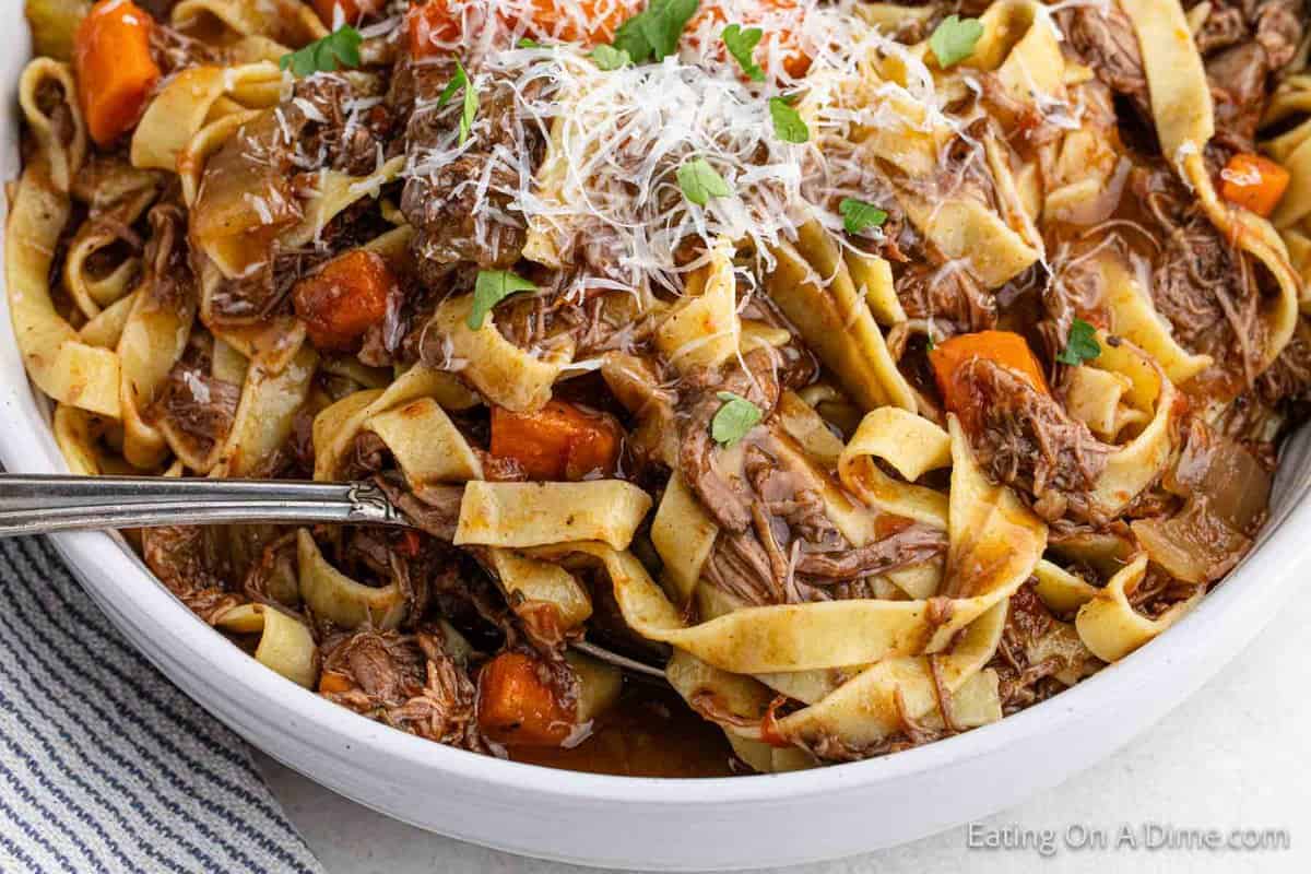 Beef Ragu in a bowl topped with shredded parmesan cheese