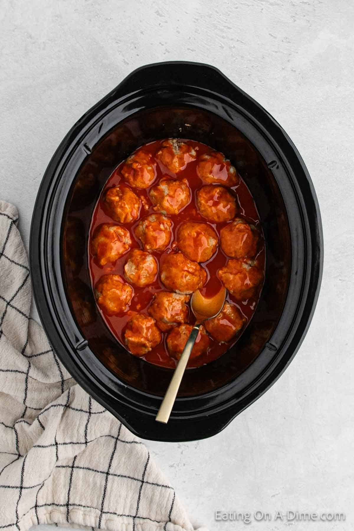 Adding meatballs to the slow cooker and combining with the sauce