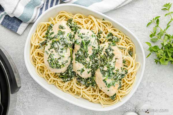 A bowl of chicken florentine with spaghetti noodles. 