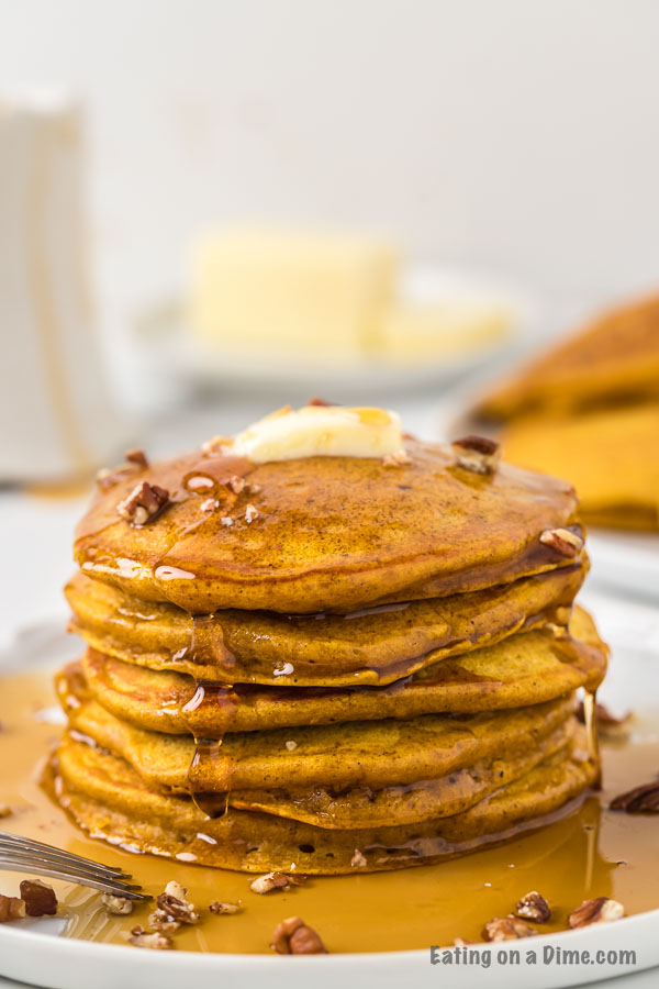 Close up image of pumpkin pancakes stacked with syrup with butter. 