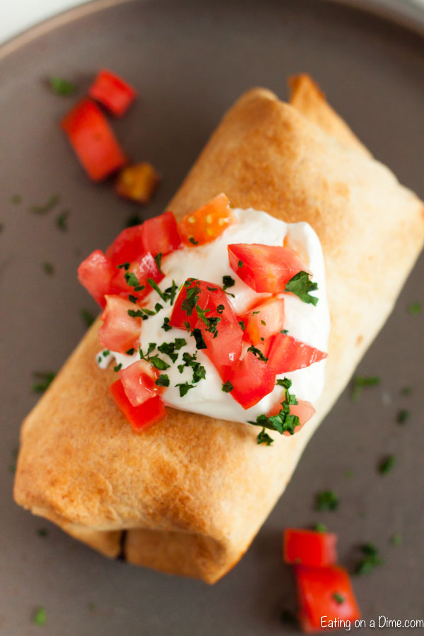 Mexican Monday just got easier thanks to Chicken Chimichangas recipe in the crock pot. Flavorful and tender chicken is slow cooked to perfection making it so easy to make homemade chimichangas. Try this chicken chimichanga recipe easy. You can bake or use the air fryer for this shredded chicken recipe. #eatingonadime #chickenchimichangas
