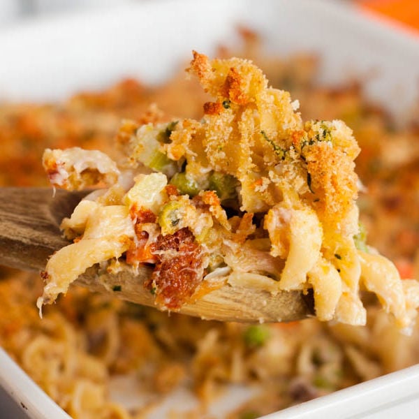 Tuna Casserole in a baking dish with a serving on a wooden spoon