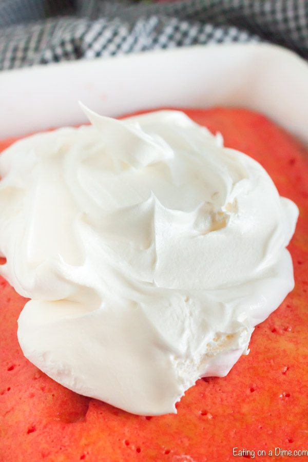 Close up image of Strawberry Jello Cake with Whipped Topping being spread on top.