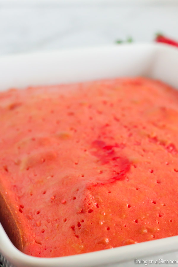 Close up image of Cake with the Strawberry Jello just poured on top. 