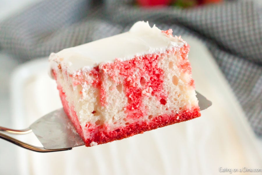 Close up image of a piece of strawberry jello cake on a spatula. 
