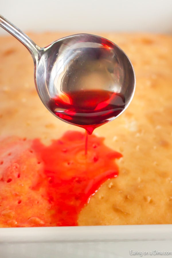 Close up image of cake having the jello being poured on top.