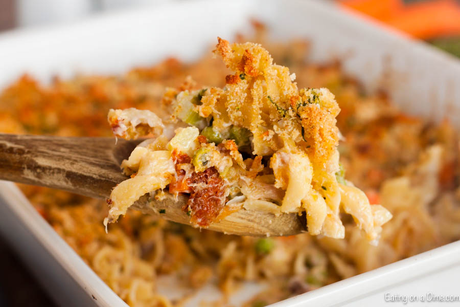 Tuna Noodle casserole with a wooden spoon serving out 1 serving of it. 