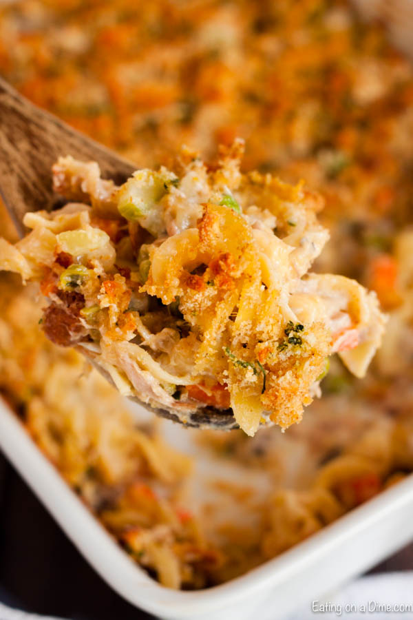 Tuna Casserole in a baking dish with a serving on a wooden spoon