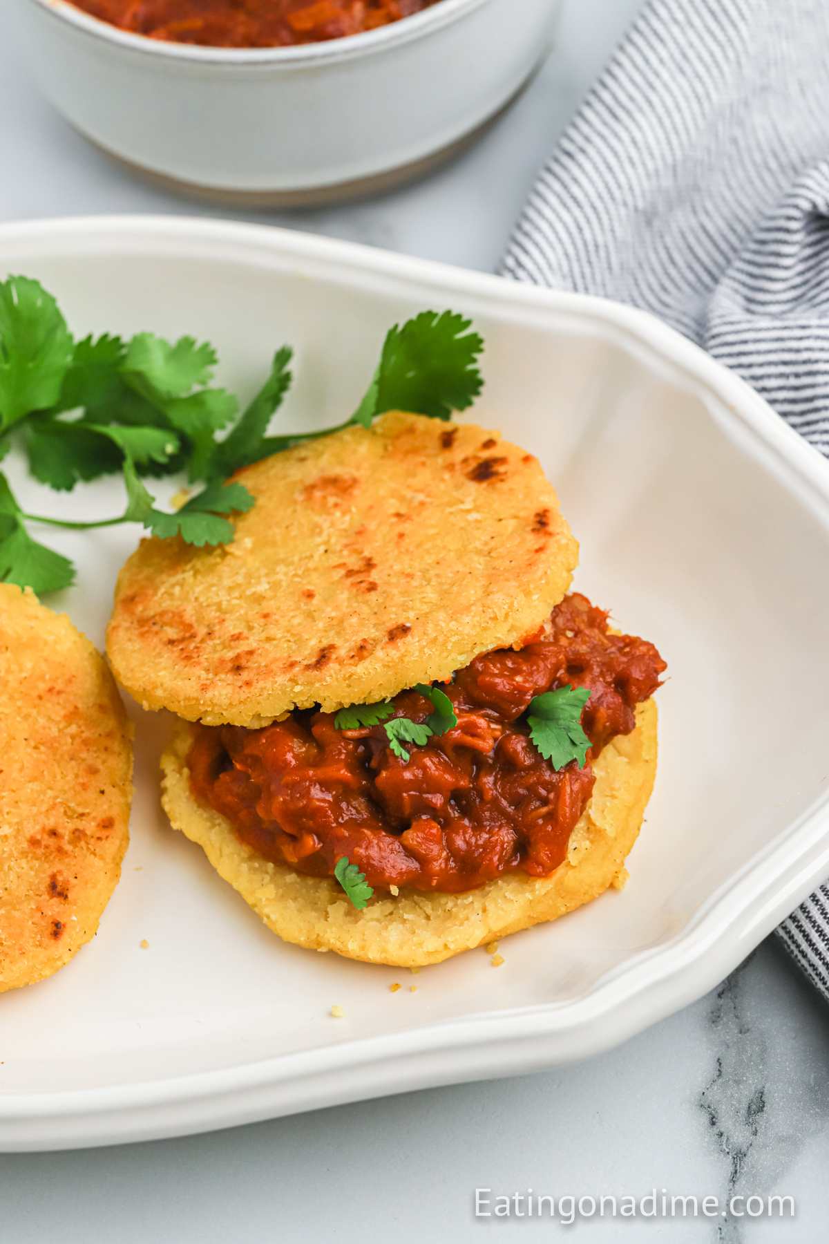Arepas on a plate topped with meat sauce