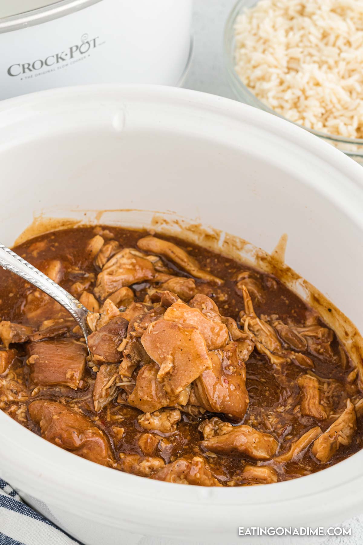 Bourbon Chicken in a crock pot with a serving on a spoon