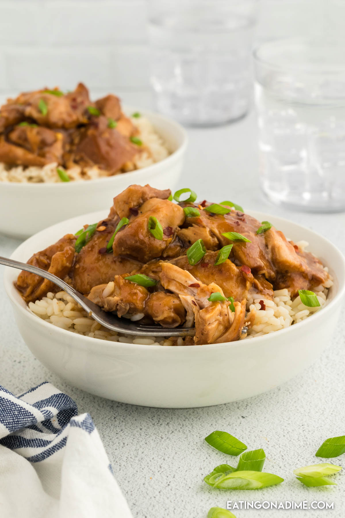 Bourbon Chicken in a white bowl served over rice with a fork
