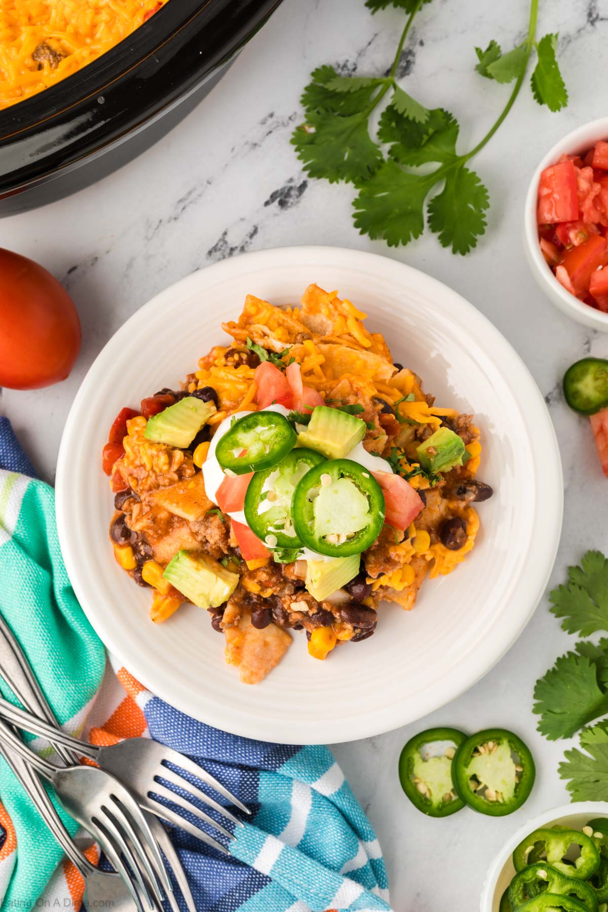 Mexican Casserole serving on a plate topped with sour cream, jalapenos, and diced avocado